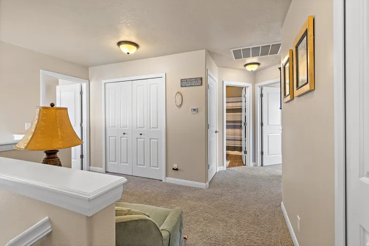 Hallway with light colored carpet and a textured ceiling