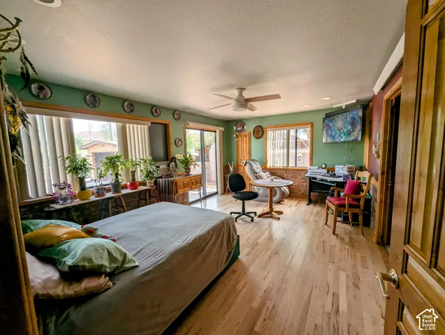 Bedroom with access to outside, hardwood / wood-style flooring, a textured ceiling, and a ceiling fan