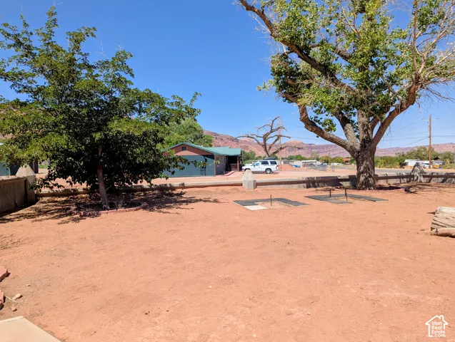 Spacious outdoor area with natural ground cover, mature shade trees, and built-in horseshoe pits