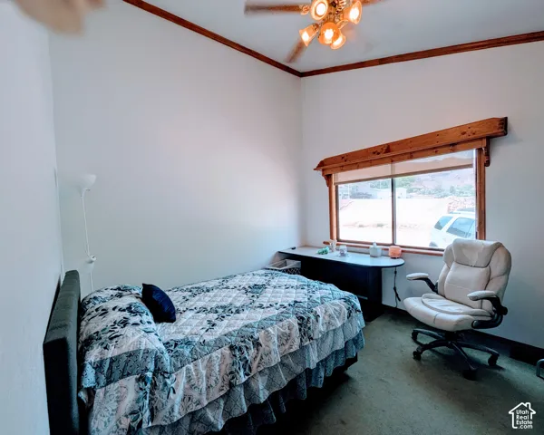 Bedroom with carpet, ornamental molding, and ceiling fan
