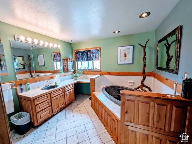 Bathroom with vanity, a bath, a textured ceiling, and light tile patterned flooring