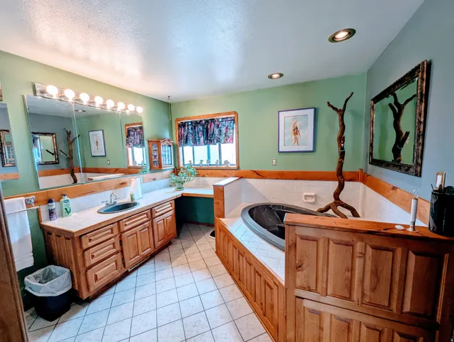 Bathroom with vanity, a bath, a textured ceiling, and light tile patterned flooring