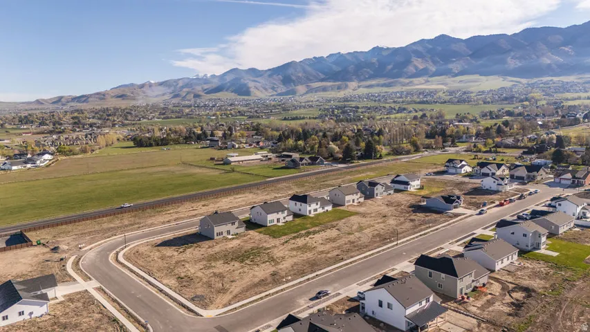 Aerial view of property and surrounding area featuring a mountain backdrop and nearby suburban area