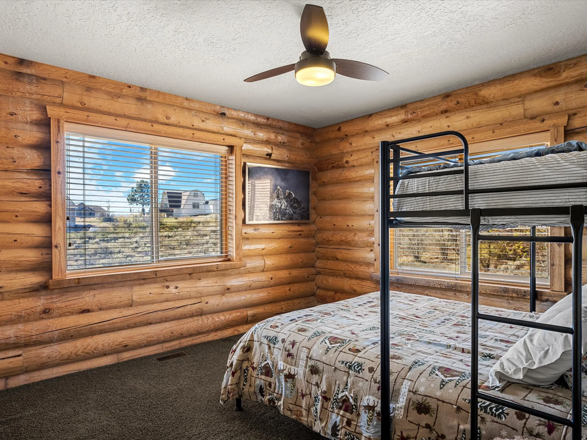 Bedroom featuring dark colored carpet, a textured ceiling, rustic walls, and a ceiling fan