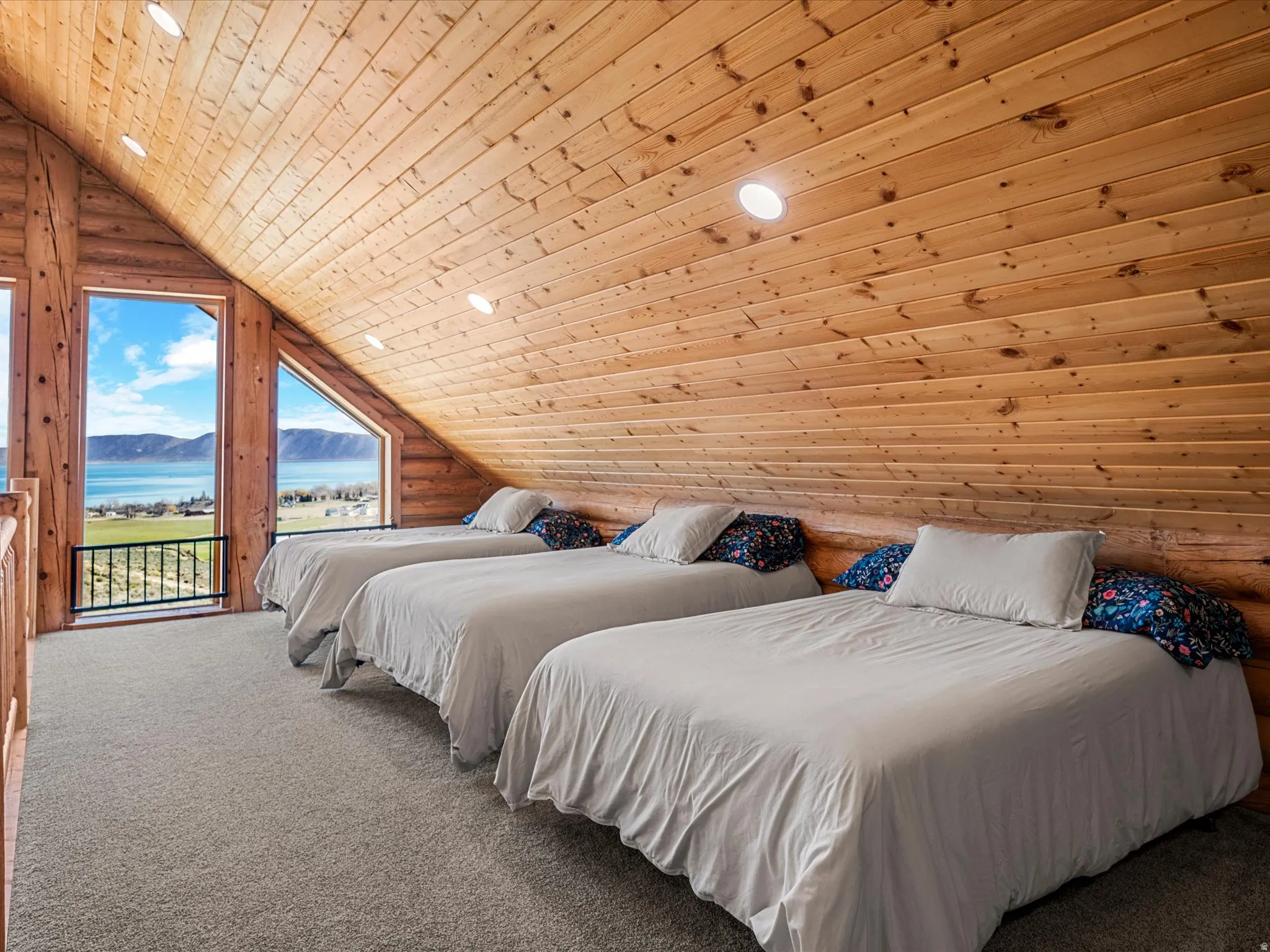 Carpeted room with log walls, a vaulted wood ceiling, recessed lighting, and a water and mountain view