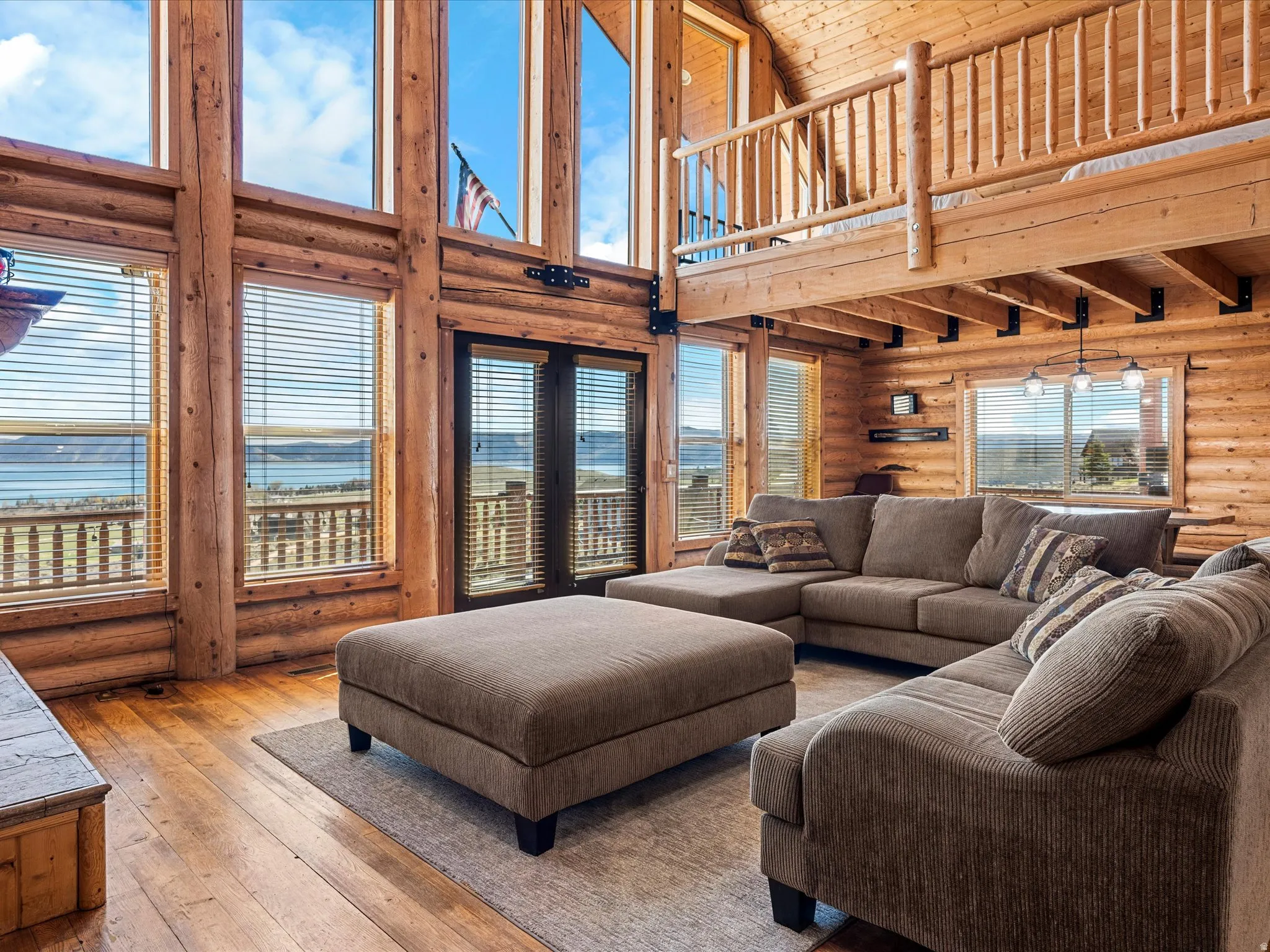 Living area with rustic walls, hardwood / wood-style floors, a water view, and a high wood ceiling