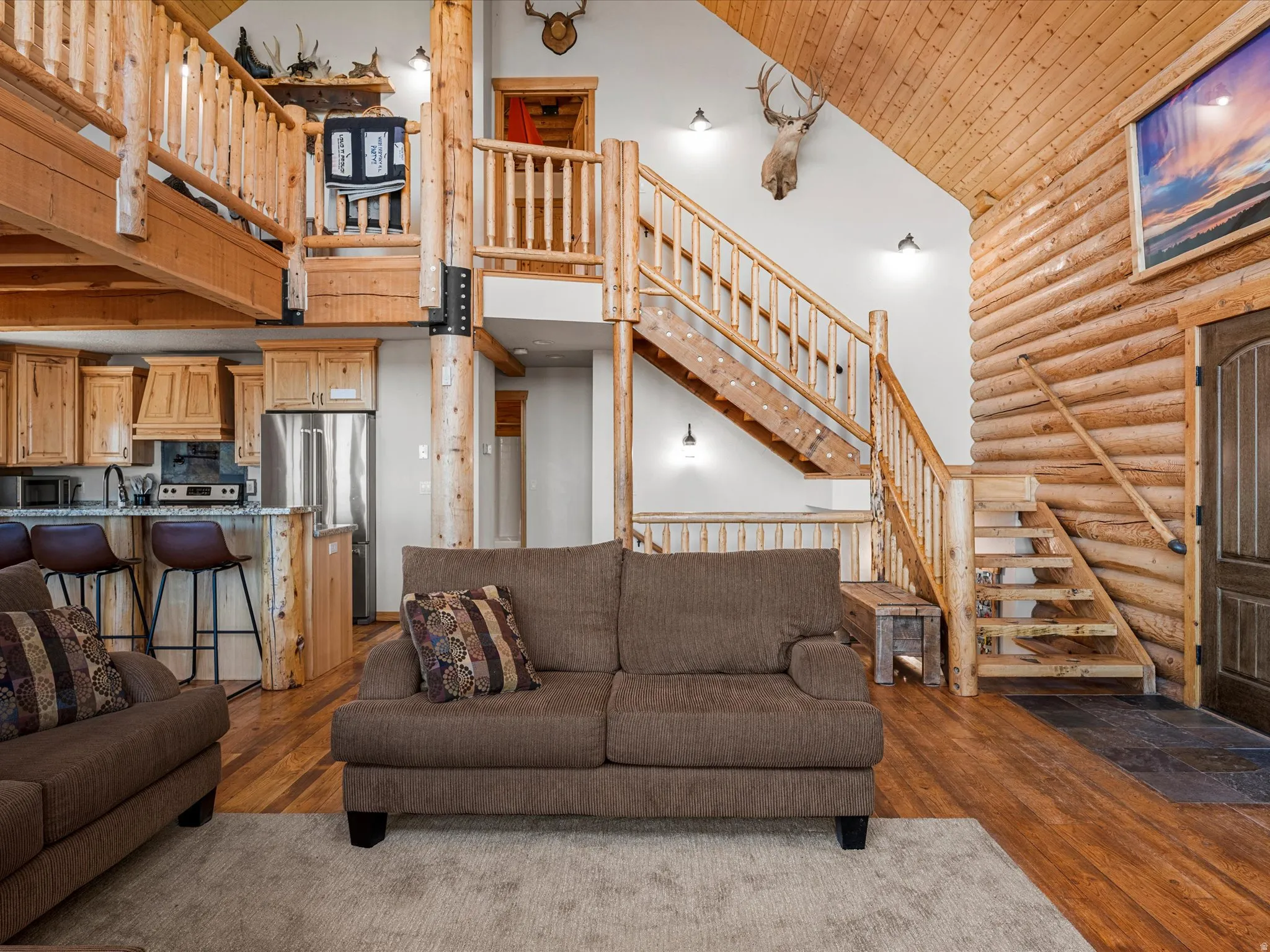 Living area with a vaulted wooden ceiling, rustic walls, and dark wood-style floors
