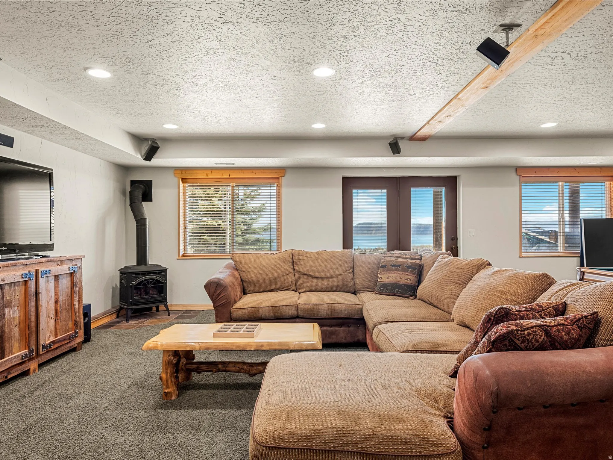 Living room with a wood stove, a textured ceiling, carpet, recessed lighting, and french doors