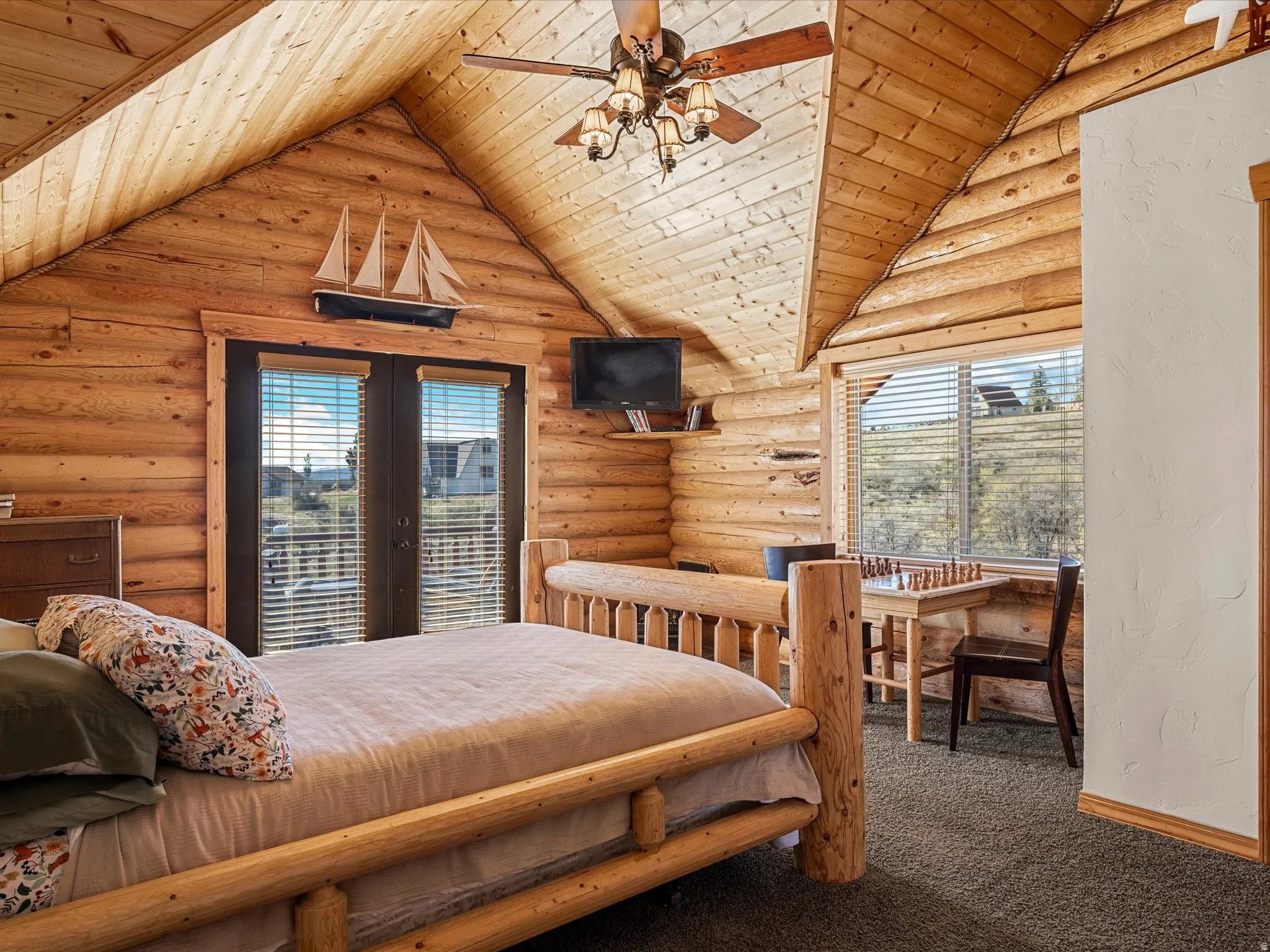 Bedroom featuring multiple windows, rustic walls, wooden ceiling, carpet floors, and french doors