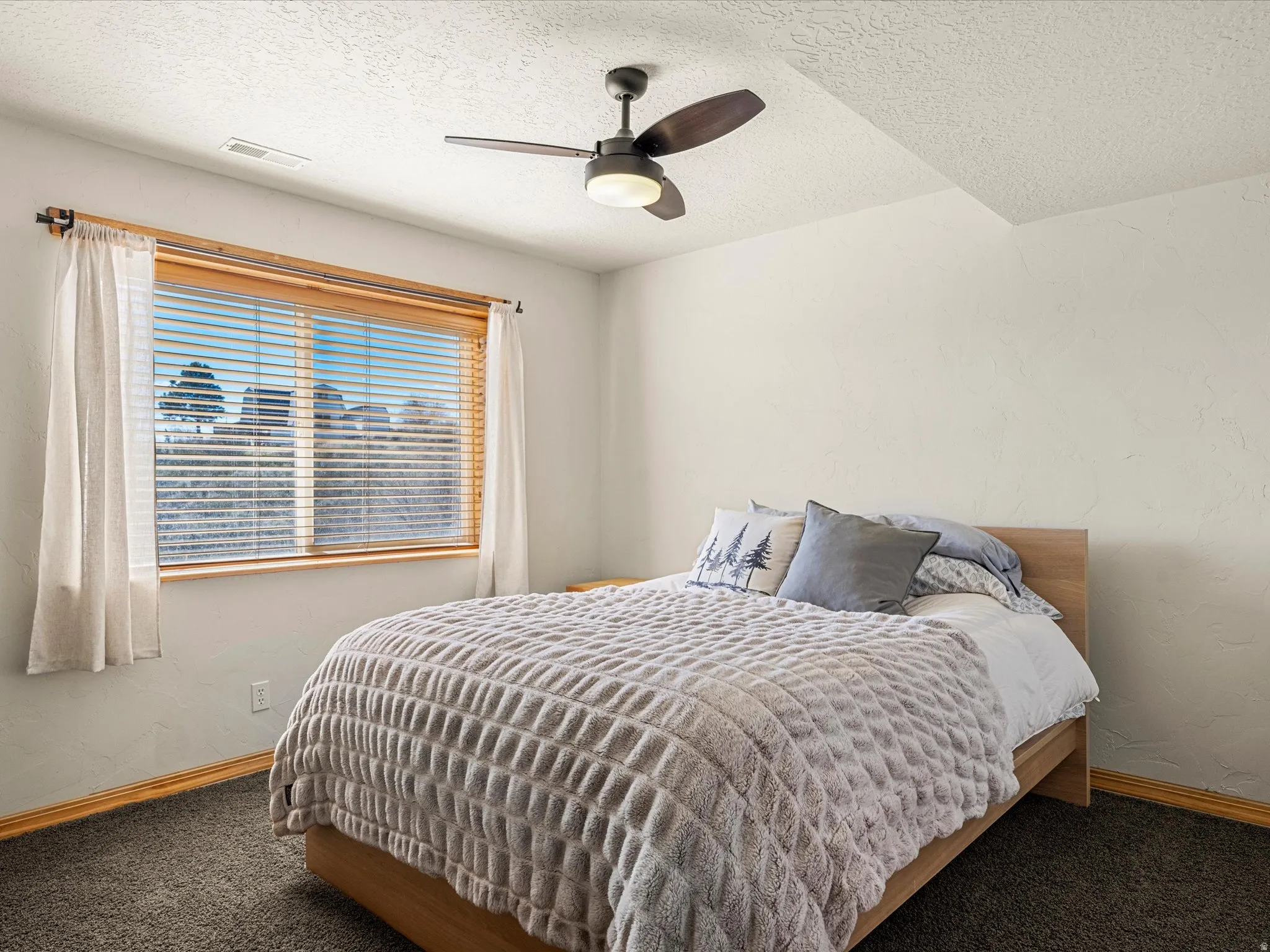Bedroom with a ceiling fan, a textured ceiling, carpet flooring, and a textured wall