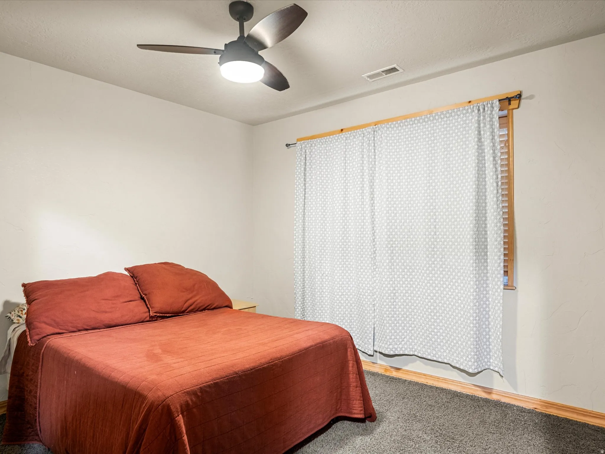 Bedroom with carpet flooring, a ceiling fan, and a textured ceiling