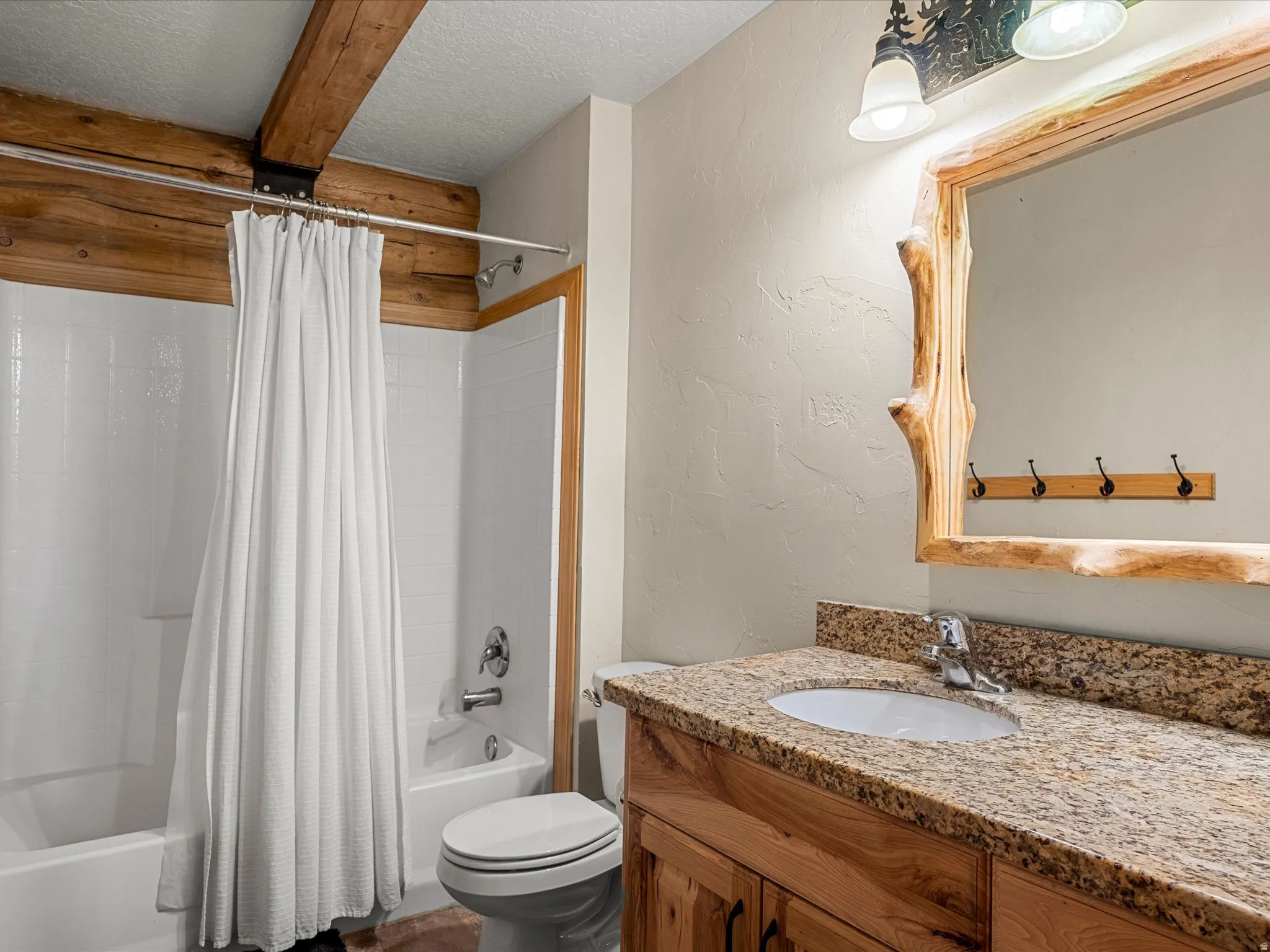 Full bath featuring a textured wall, a textured ceiling, vanity, and shower / tub combo with curtain