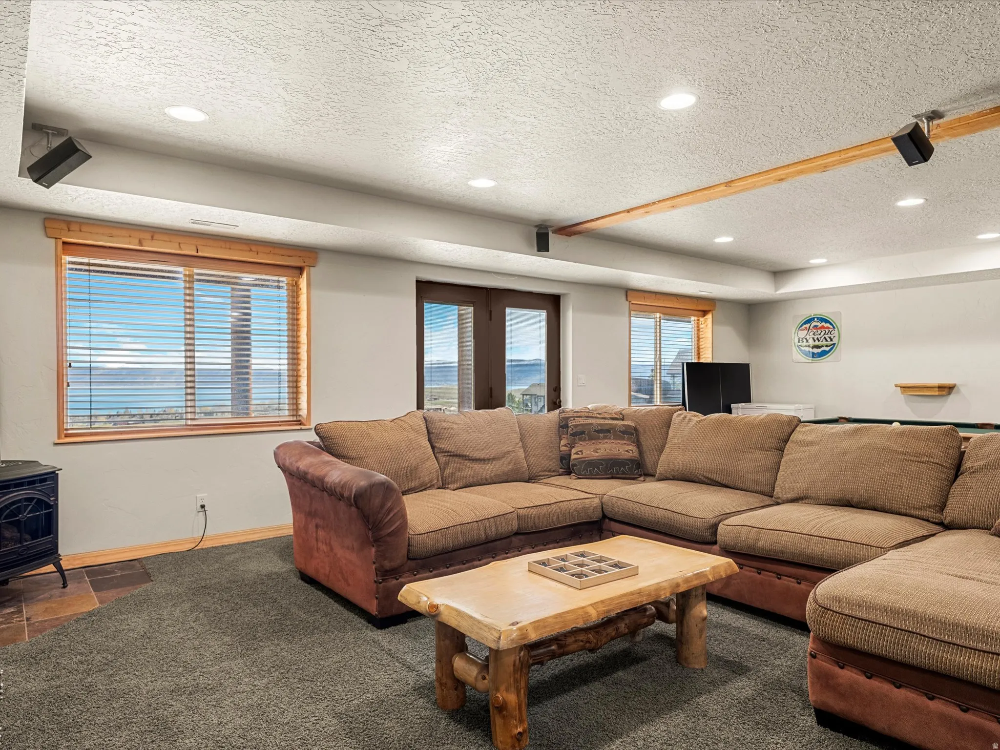 Carpeted living room featuring a wood stove, a textured ceiling, and recessed lighting