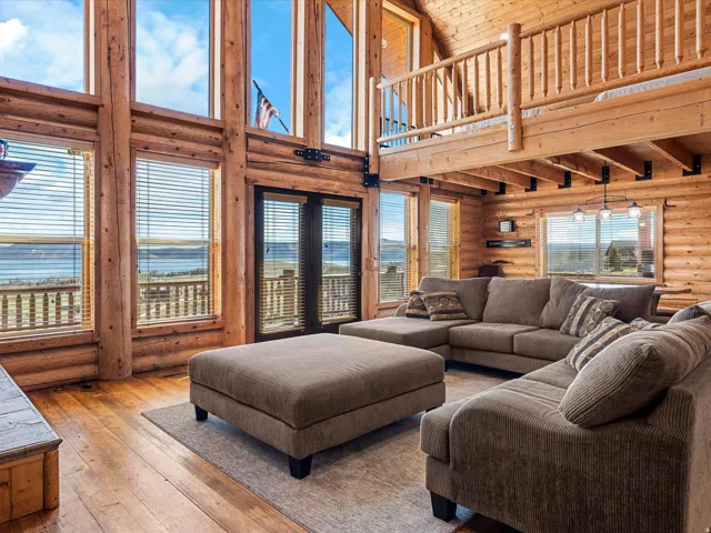 Living area with rustic walls, hardwood / wood-style floors, a water view, and a high wood ceiling