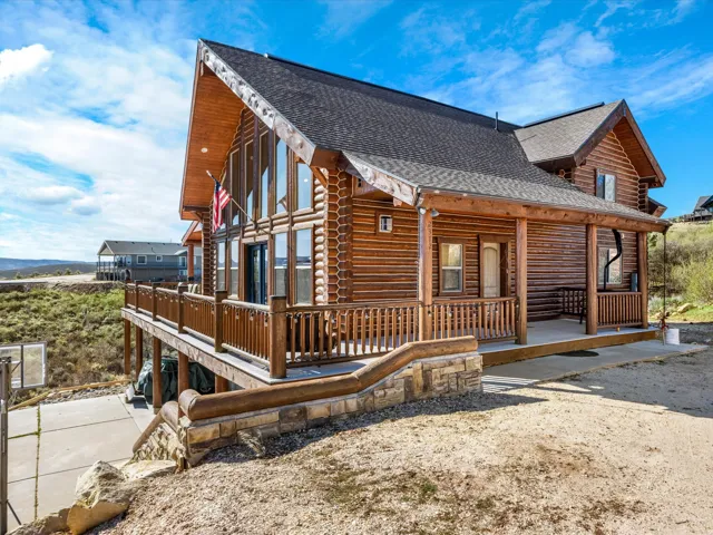 View of side of property with roof with shingles, log exterior, and a porch
