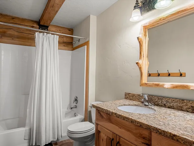Full bath featuring a textured wall, a textured ceiling, vanity, and shower / tub combo with curtain