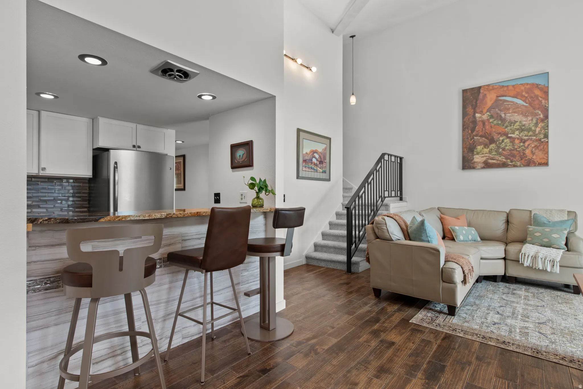 Living area with dark wood-type flooring, recessed lighting, and a high ceiling