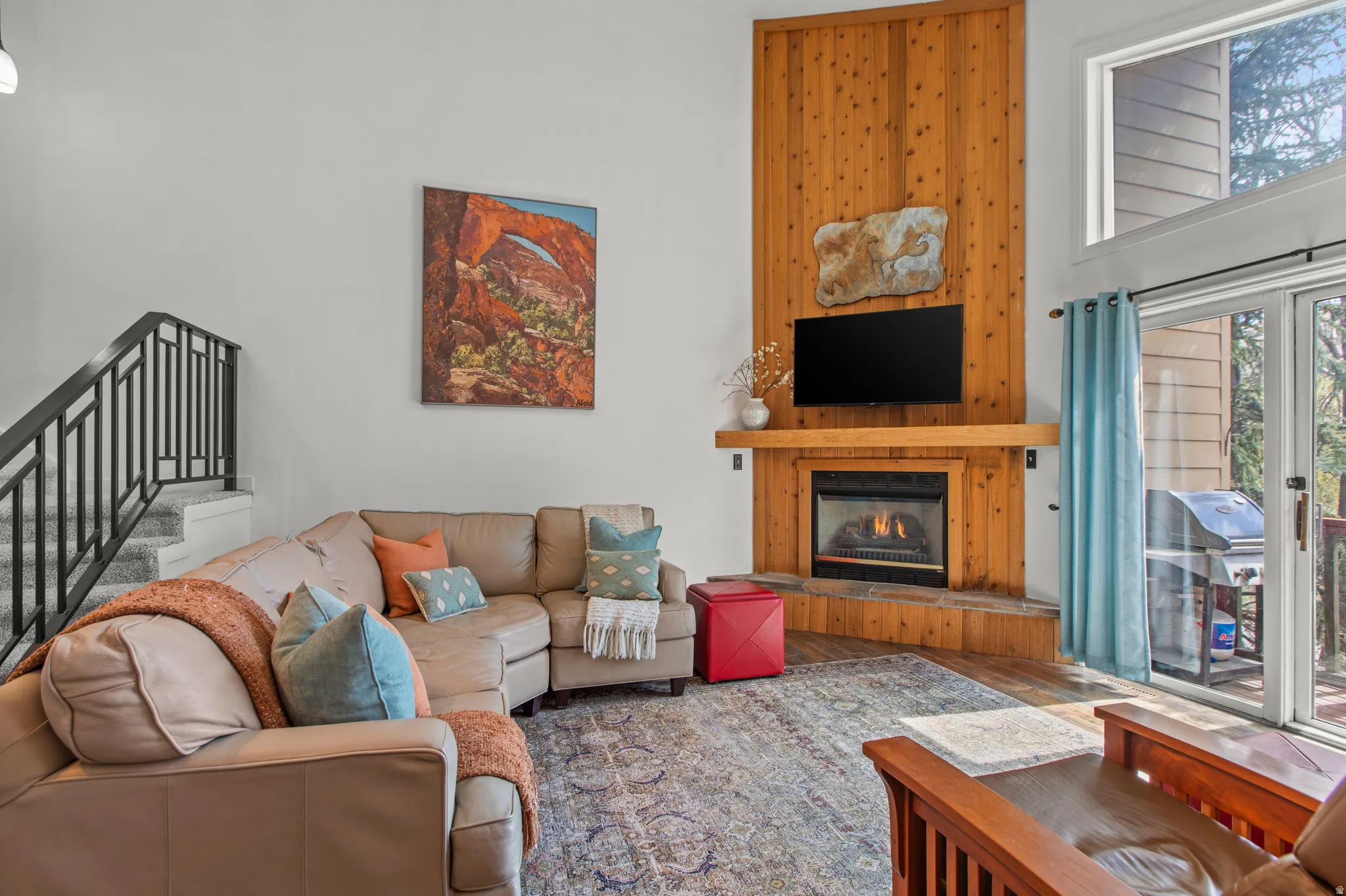 Living area with a high ceiling, wood finished floors, and a glass covered fireplace
