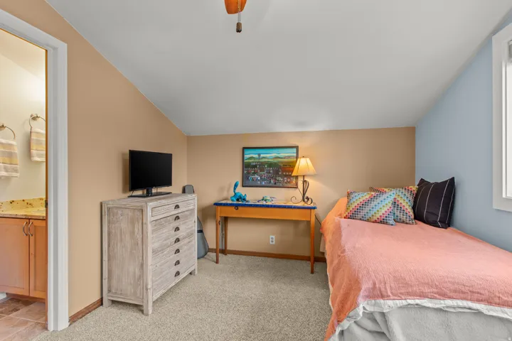 Bedroom featuring vaulted ceiling, carpet floors, a ceiling fan, and ensuite bathroom