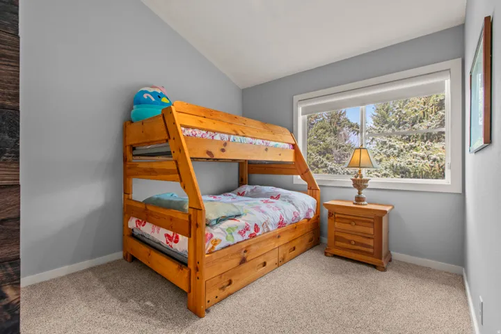 Bedroom with light carpet and vaulted ceiling