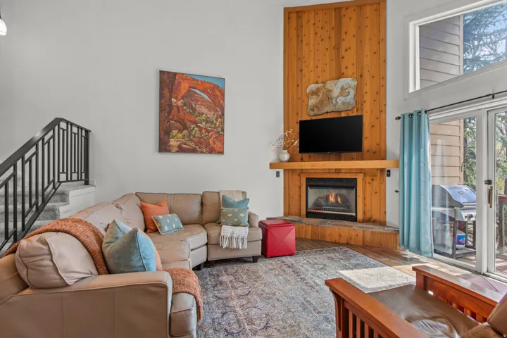 Living area with a high ceiling, wood finished floors, and a glass covered fireplace