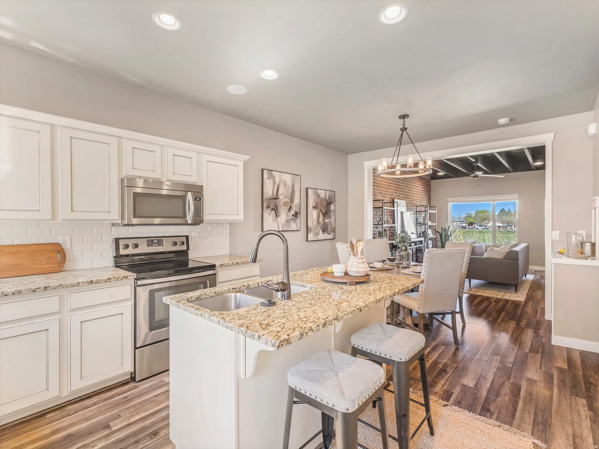 Kitchen featuring stainless steel appliances, white cabinets, light stone counters, and tasteful backsplash