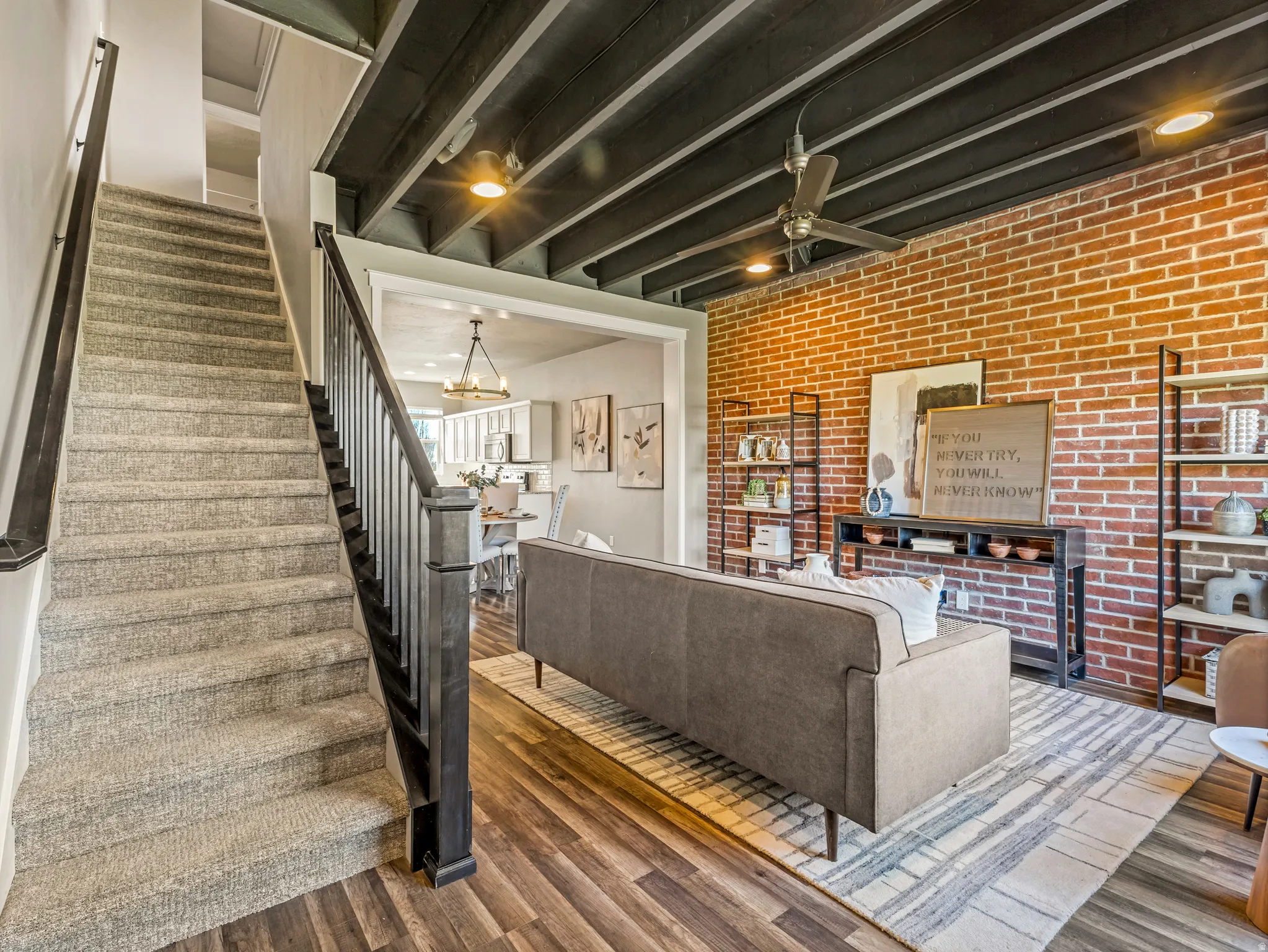 Living room with wood finished floors, brick wall, a chandelier, and ceiling fan