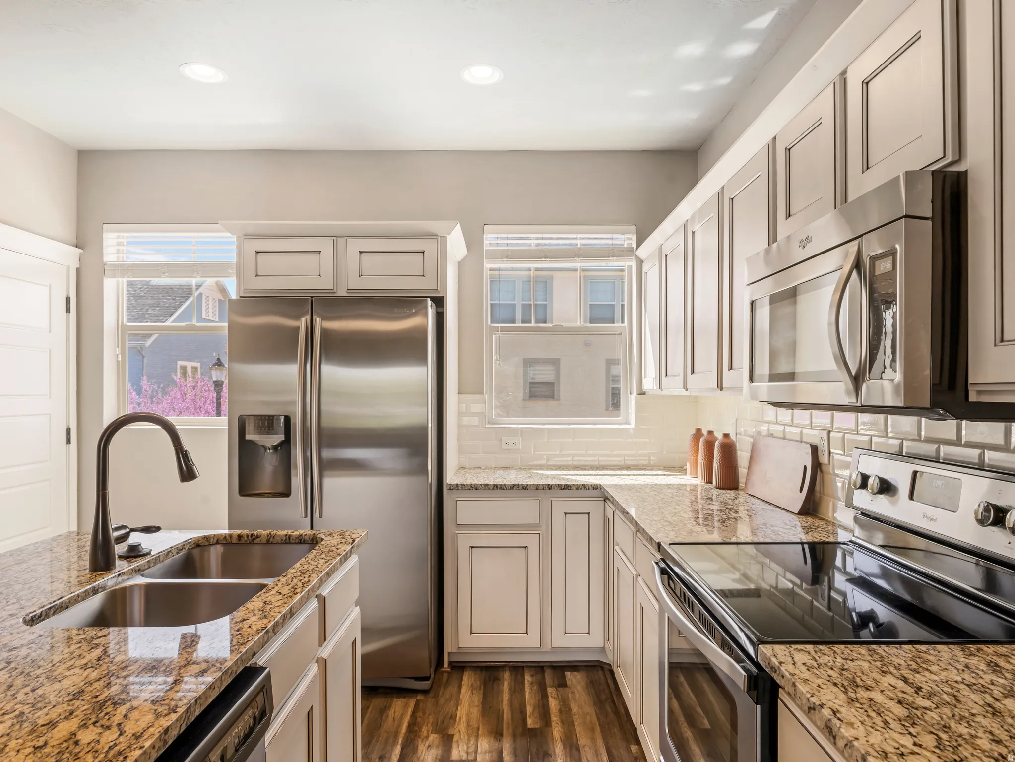 Kitchen featuring stainless steel appliances, light stone counters, dark wood-style floors, backsplash, and recessed lighting