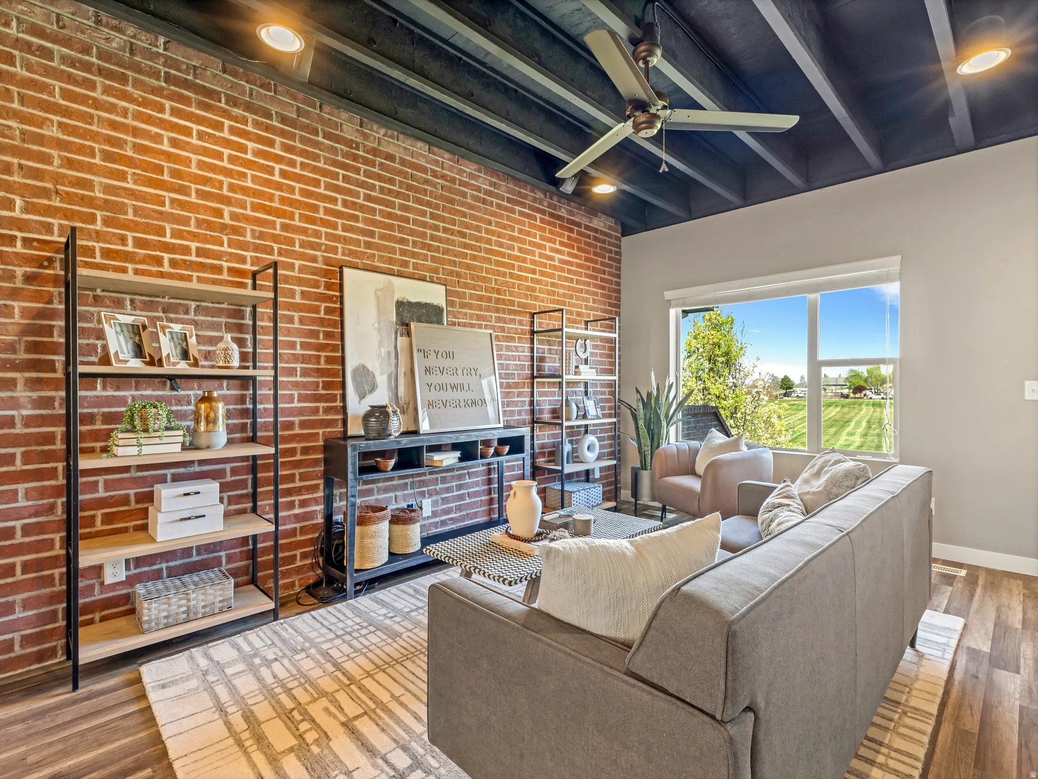 Living room with wood-type flooring, brick wall, beamed ceiling, and ceiling fan