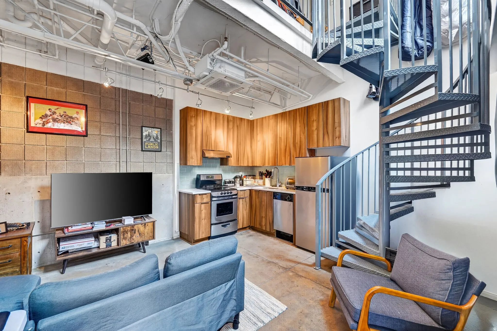 Kitchen featuring concrete flooring, light countertops, wood finish cabinetry, stainless steel appliances, and rail lighting