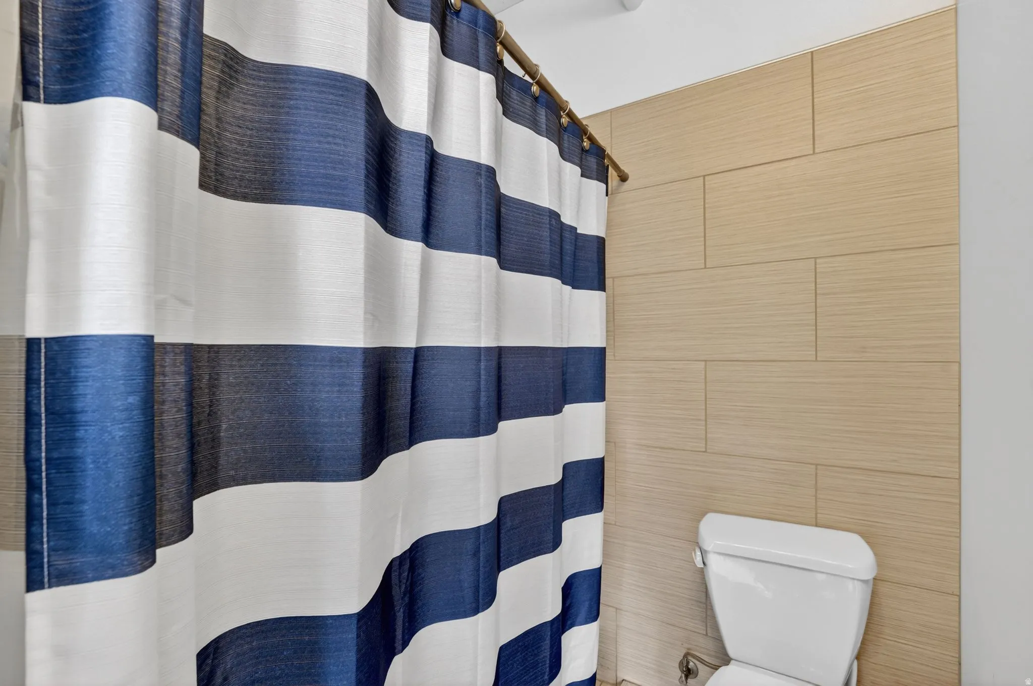 Full bath featuring a shower with curtain and tile walls