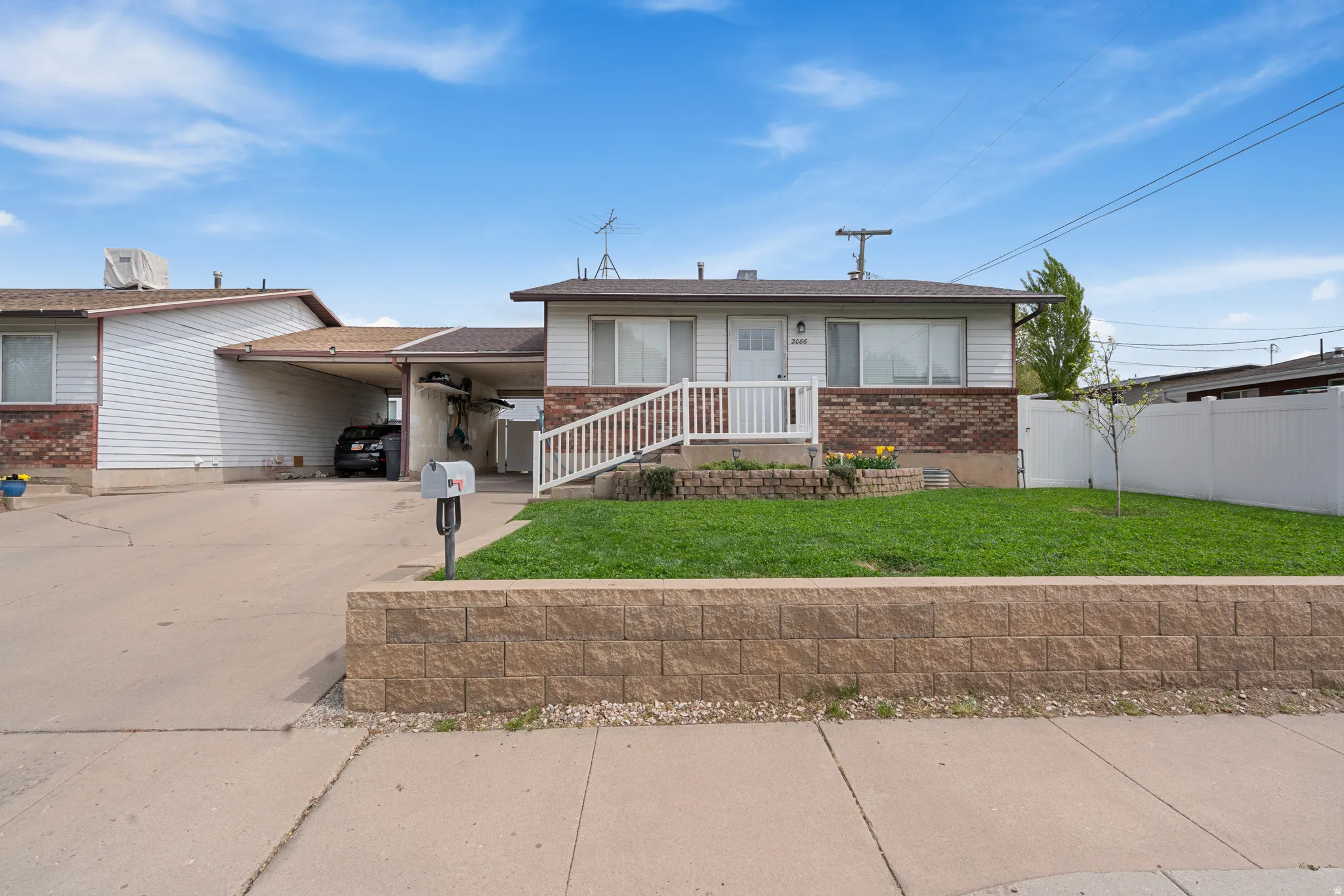 View of front of house featuring driveway, a carport, and brick siding