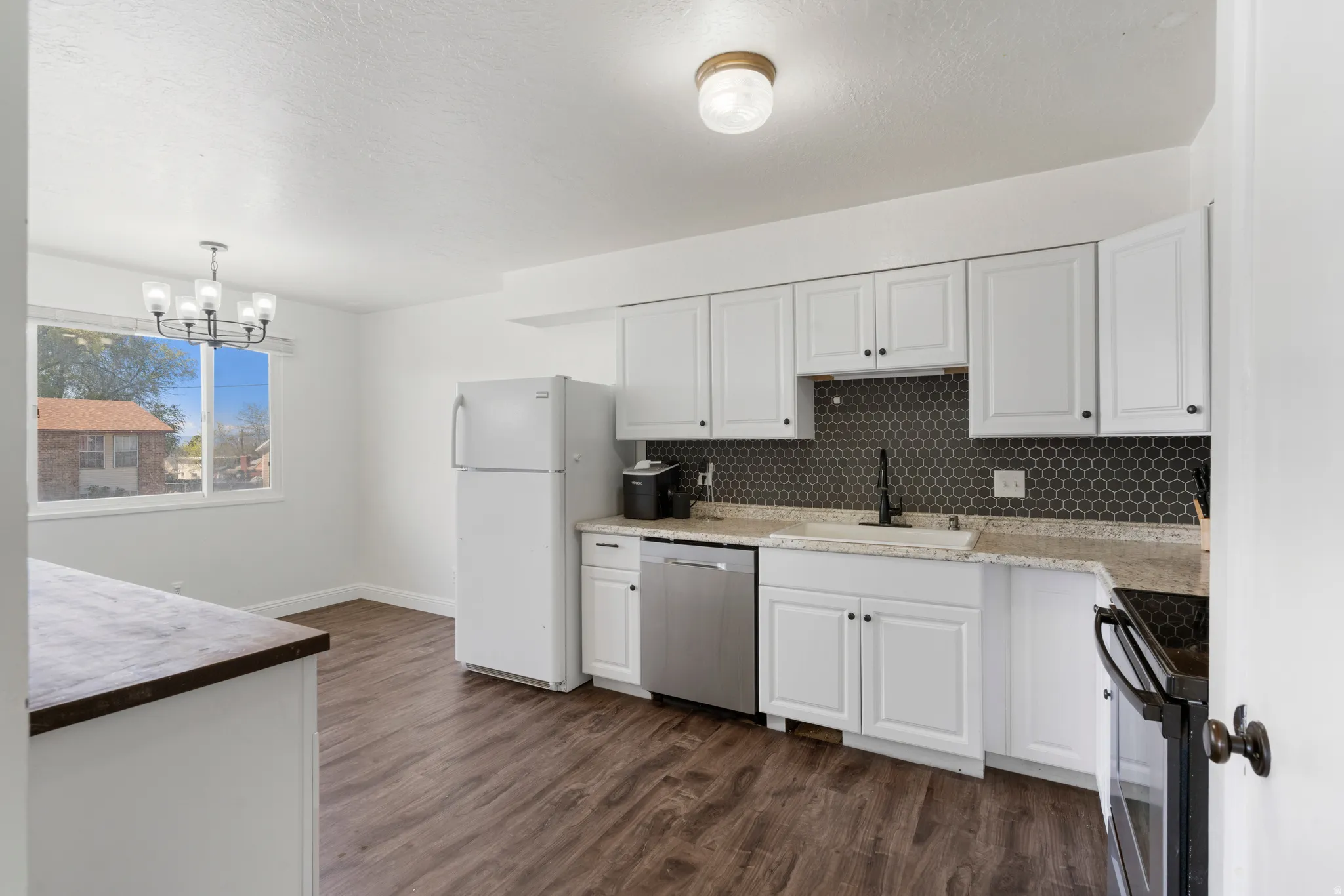 Kitchen featuring white cabinetry, black range with electric stovetop, stainless steel dishwasher, dark wood finished floors, and a textured ceiling