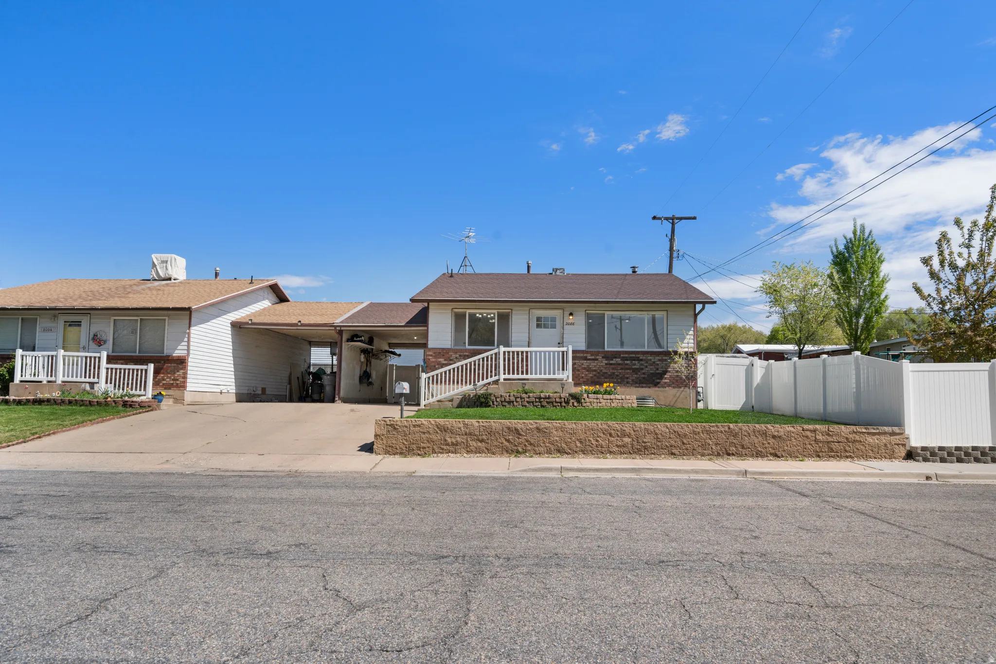 View of front of home featuring concrete driveway, brick siding, and a carport