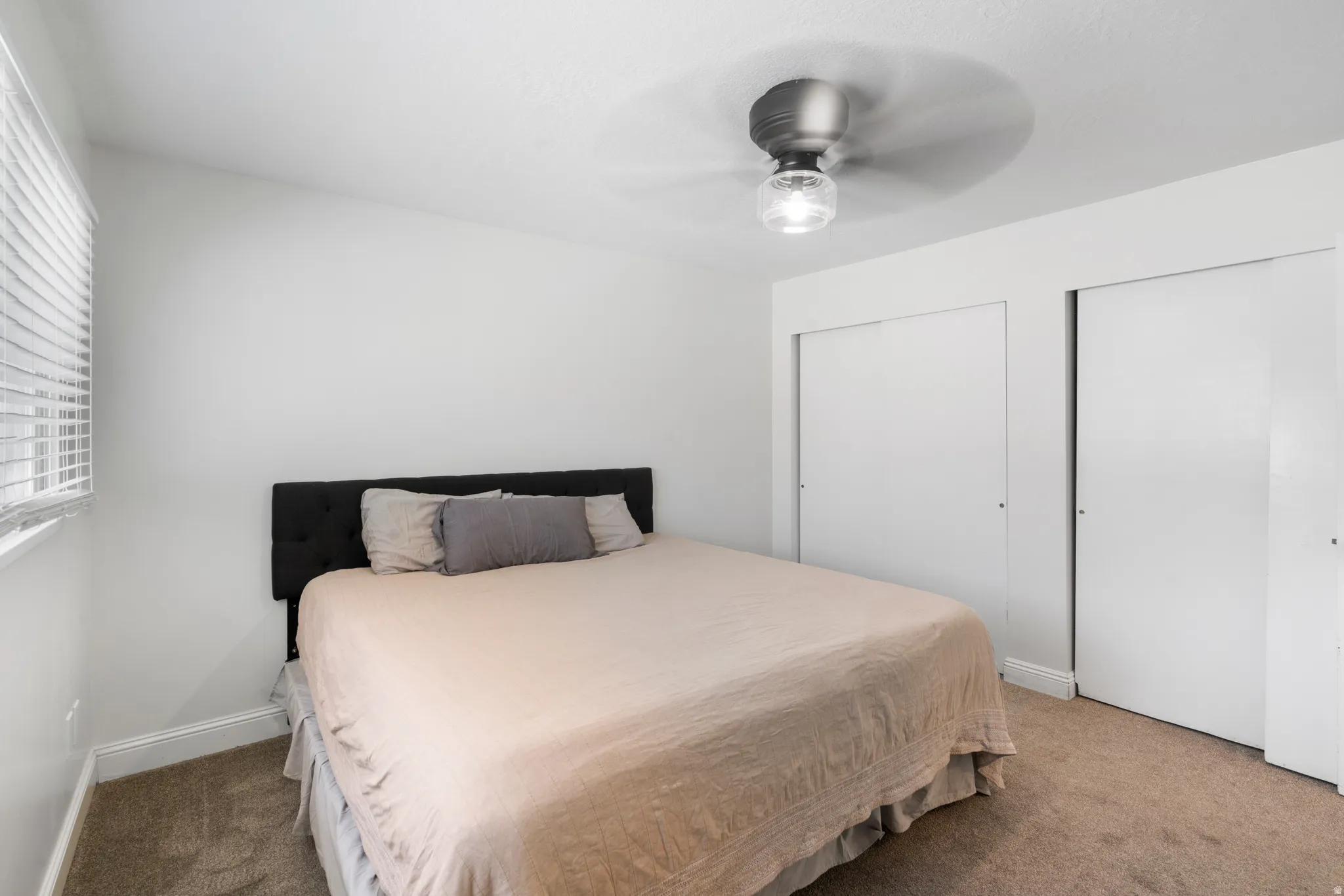 Bedroom with multiple closets, carpet flooring, and a ceiling fan
