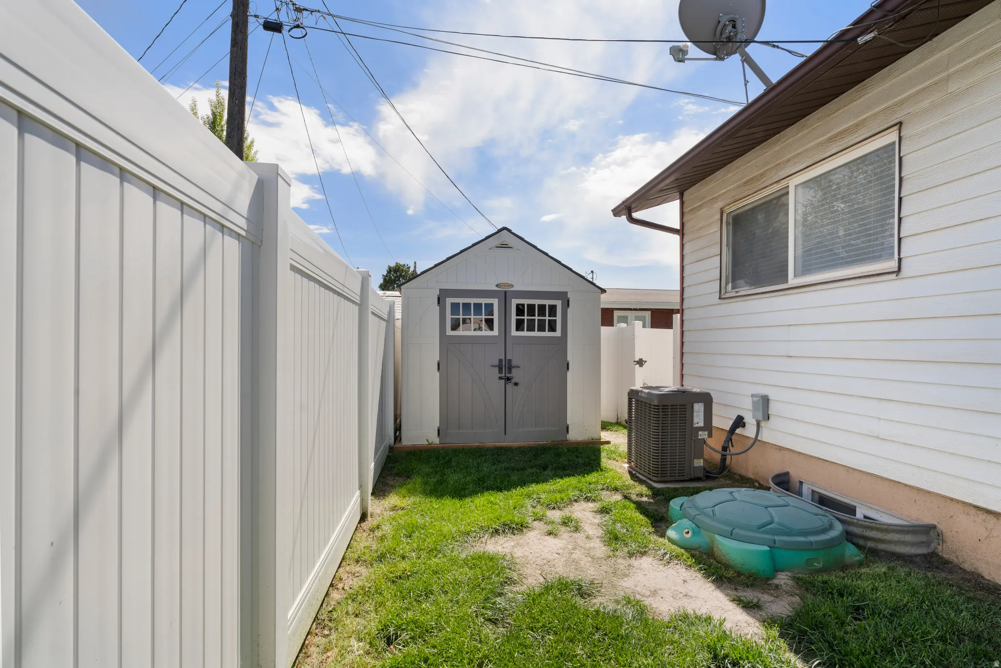 Fenced backyard featuring a storage unit