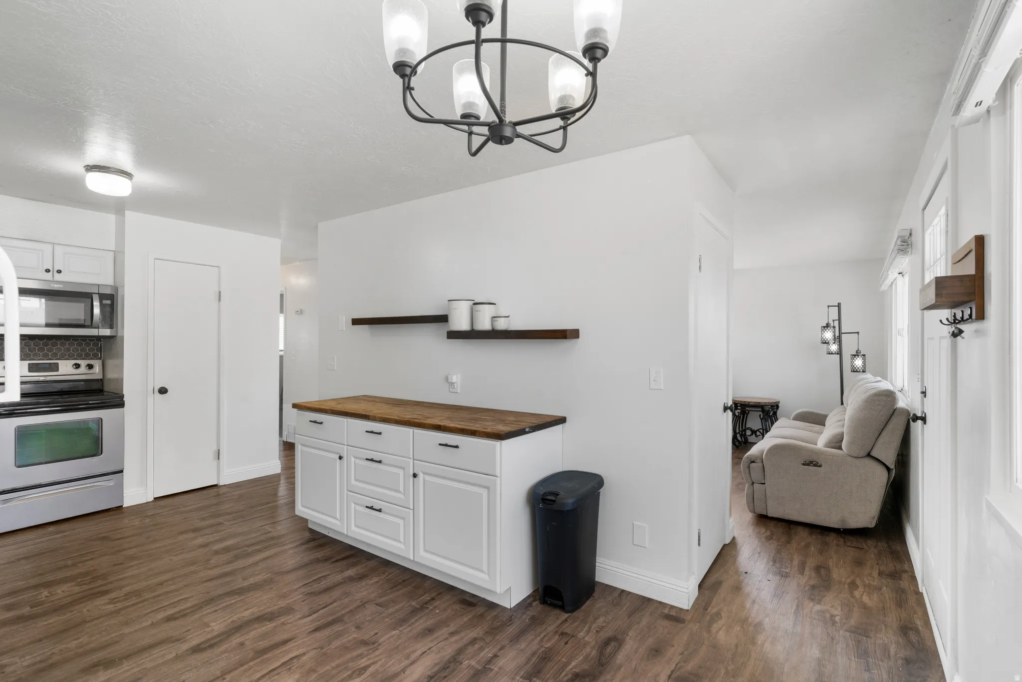 Kitchen with stainless steel appliances, white cabinetry, wood counters, open shelves, and dark wood-type flooring