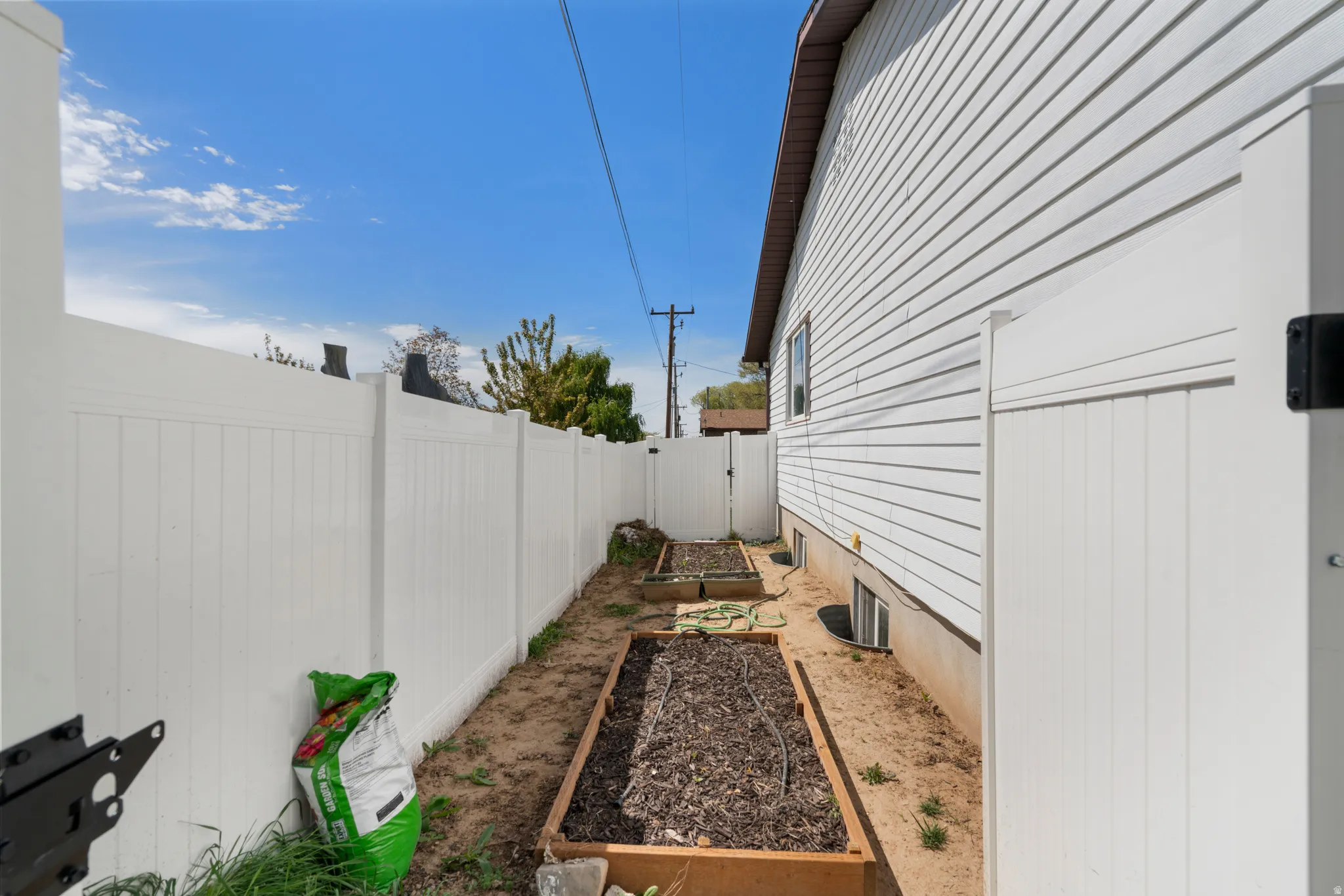 View of side of home featuring a vegetable garden, a fenced backyard, and a gate