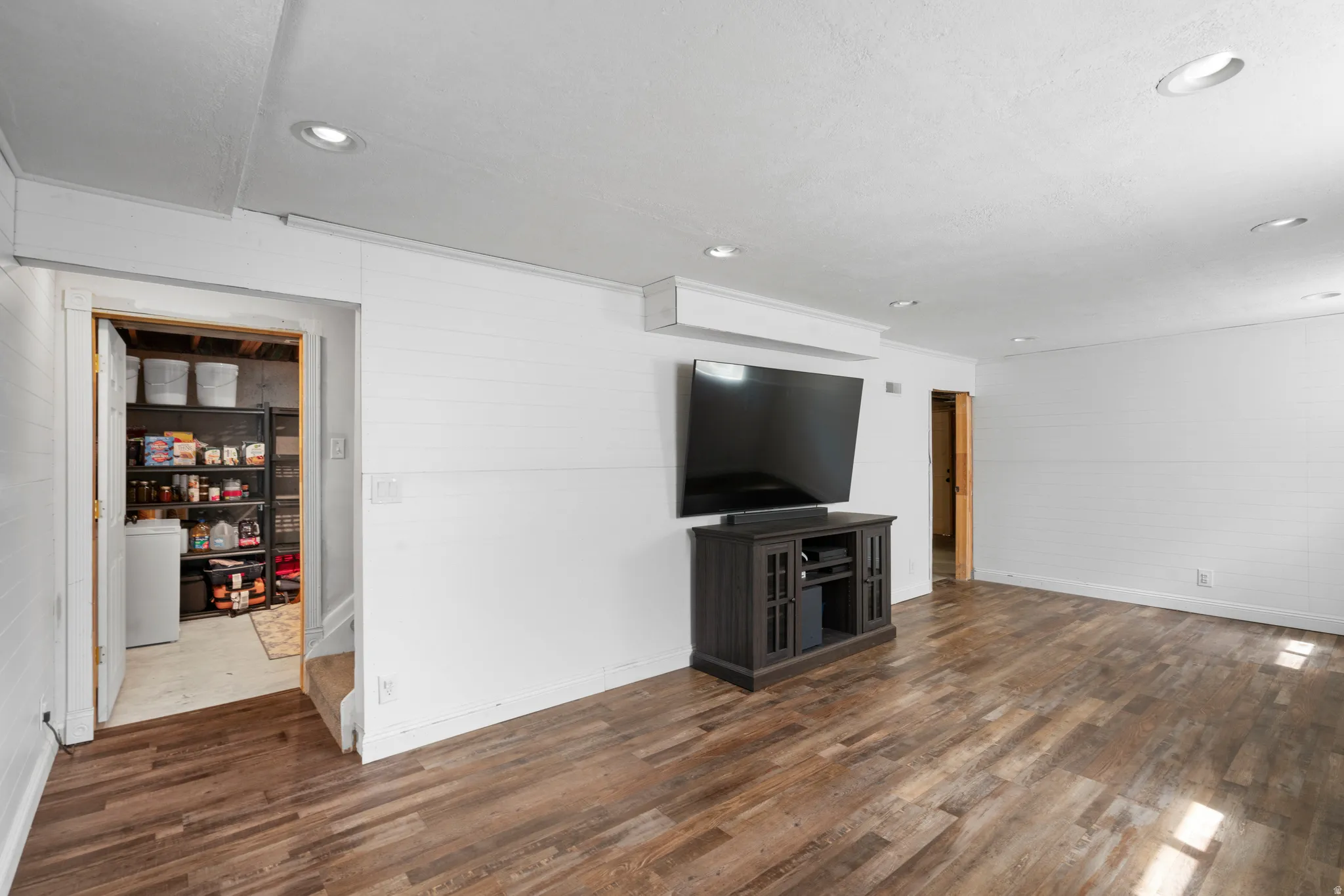 Unfurnished living room with dark wood finished floors, wooden walls, and recessed lighting