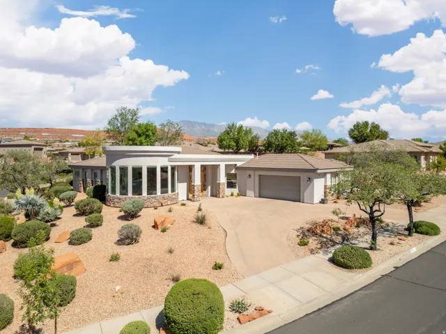 View of front of property featuring stone siding, driveway, stucco siding, and a tiled roof