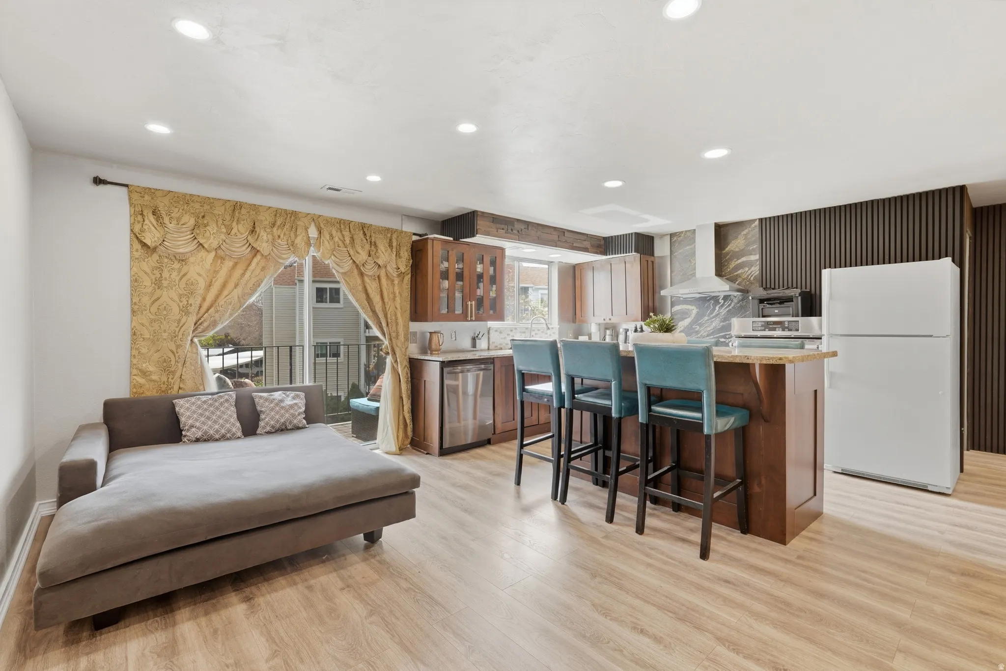 Kitchen featuring freestanding refrigerator, a kitchen breakfast bar, light wood-style floors, a center island, and wood finish cabinetry