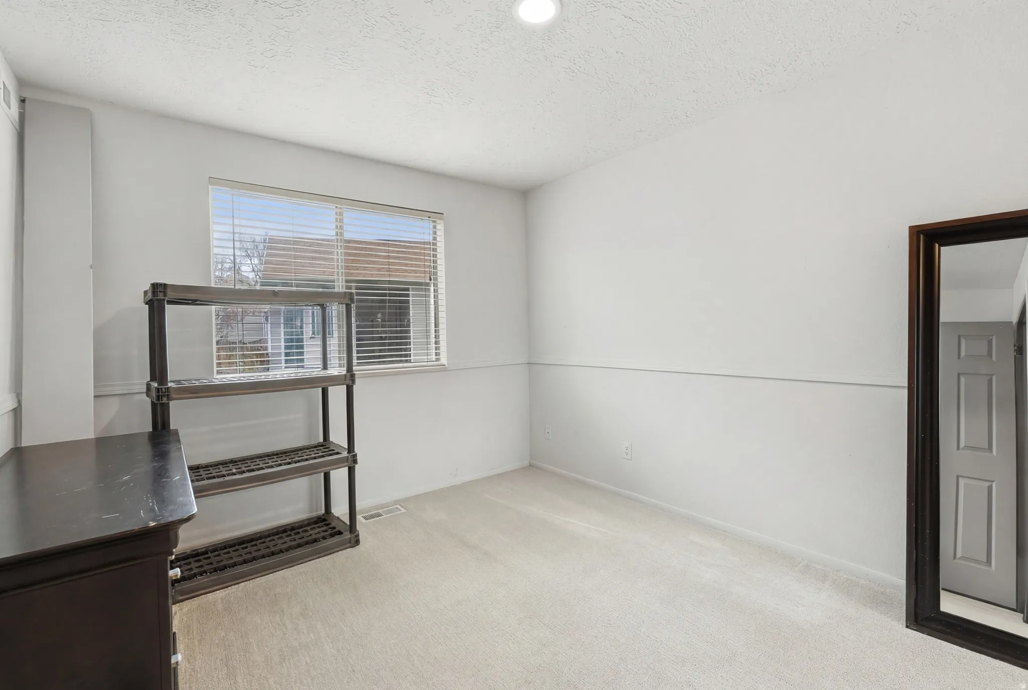 Empty room featuring light carpet and a textured ceiling