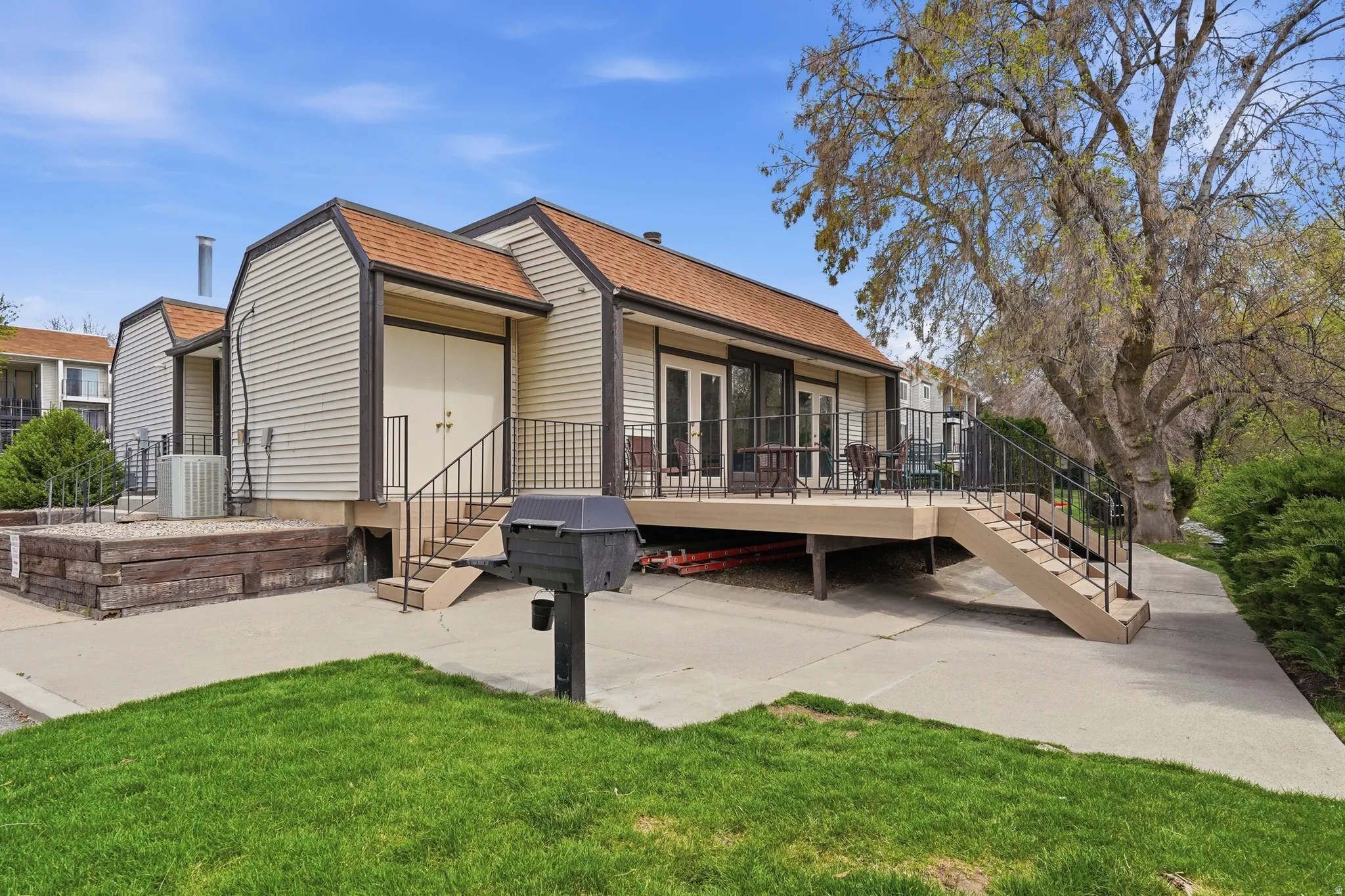 Back of property featuring roof with shingles, a lawn, a wooden deck, and a patio
