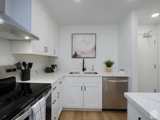 Kitchen featuring stainless steel appliances, white cabinetry, light wood finished floors, light stone countertops, and recessed lighting