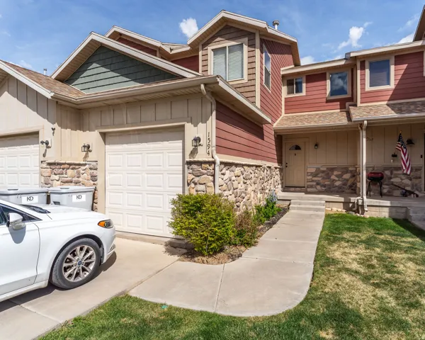 View of front facade with stone siding, board and batten siding, and a garage