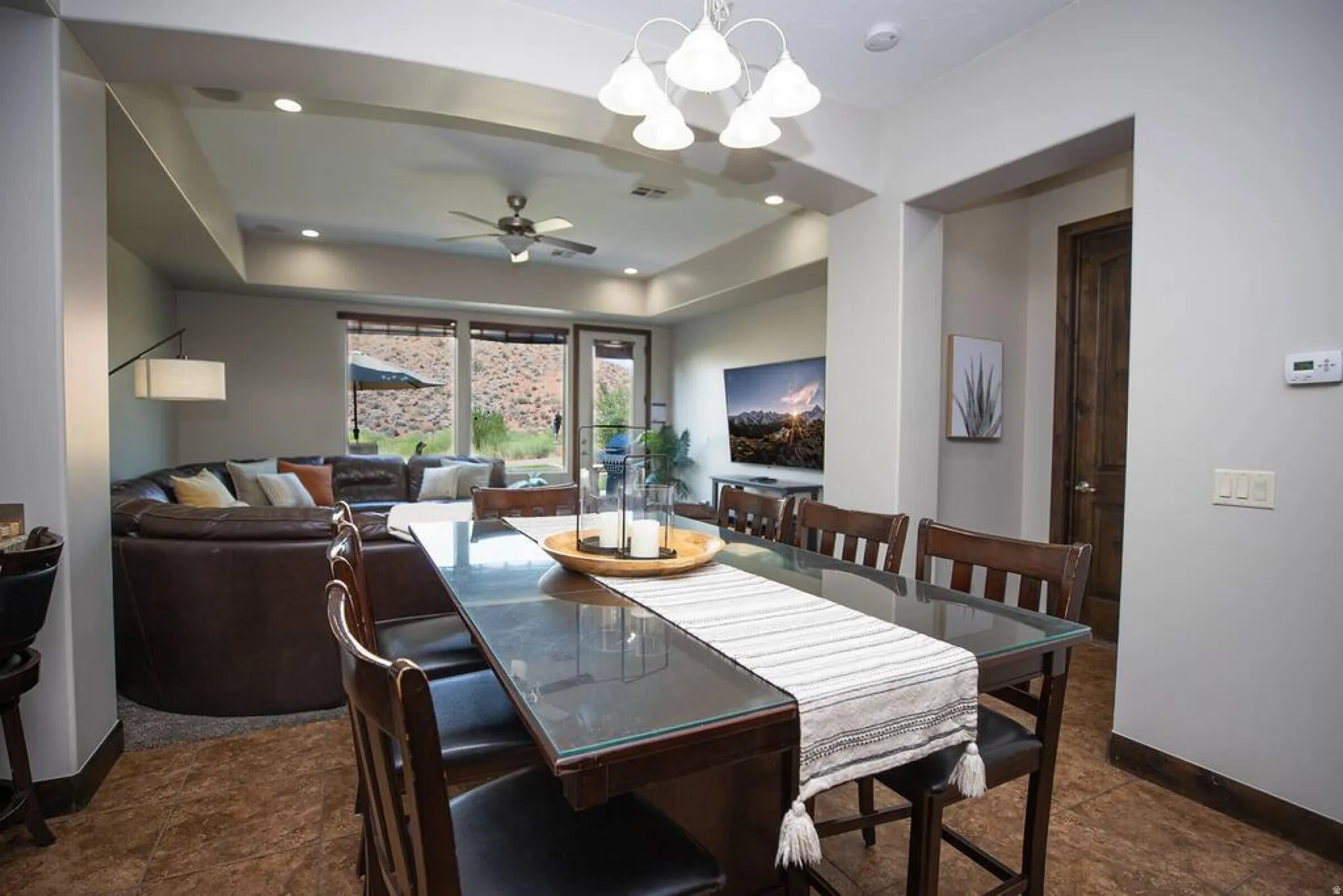 Dining area with suspended lighting, a ceiling fan, and a tray ceiling