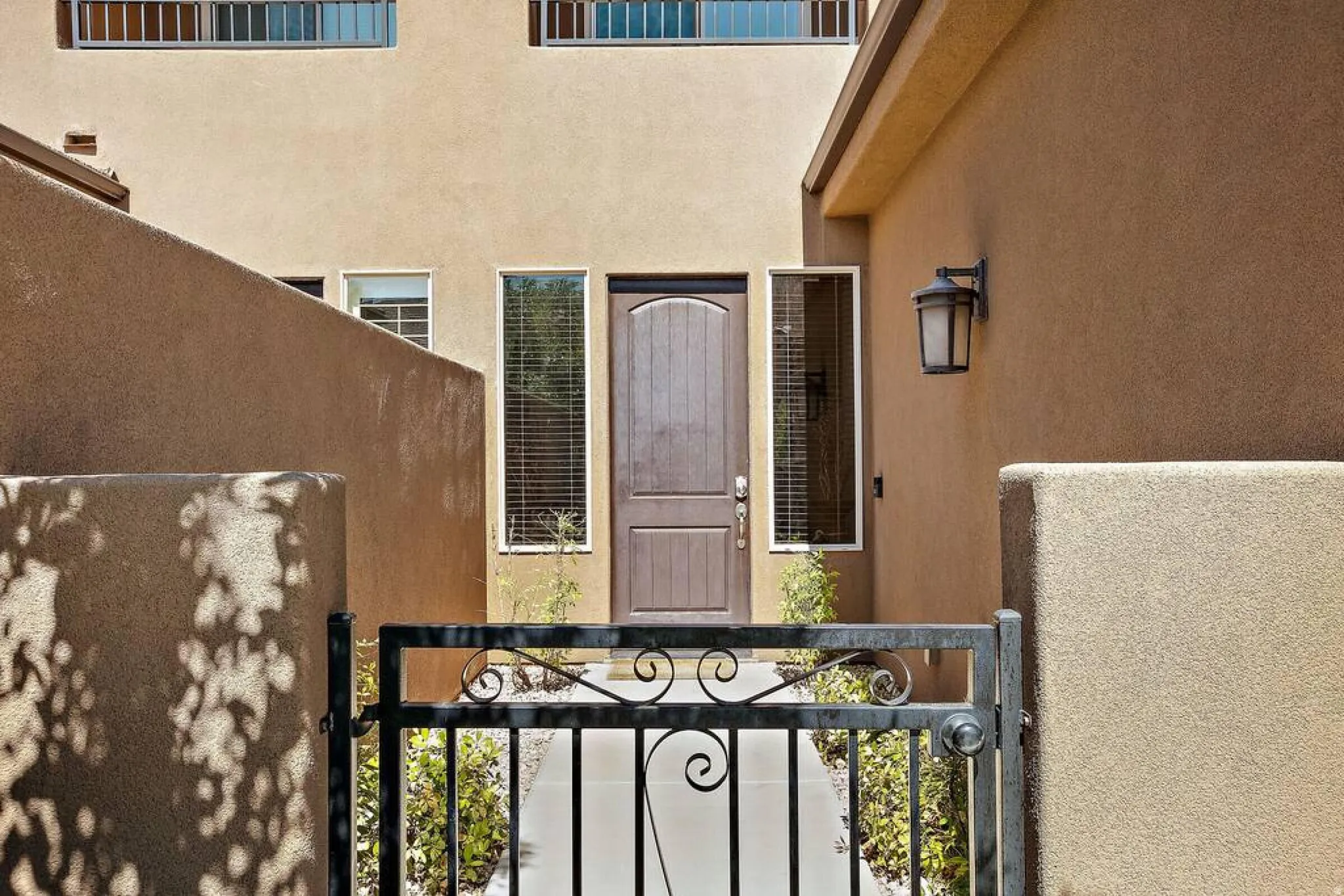 Entrance to property featuring stucco siding and a gate