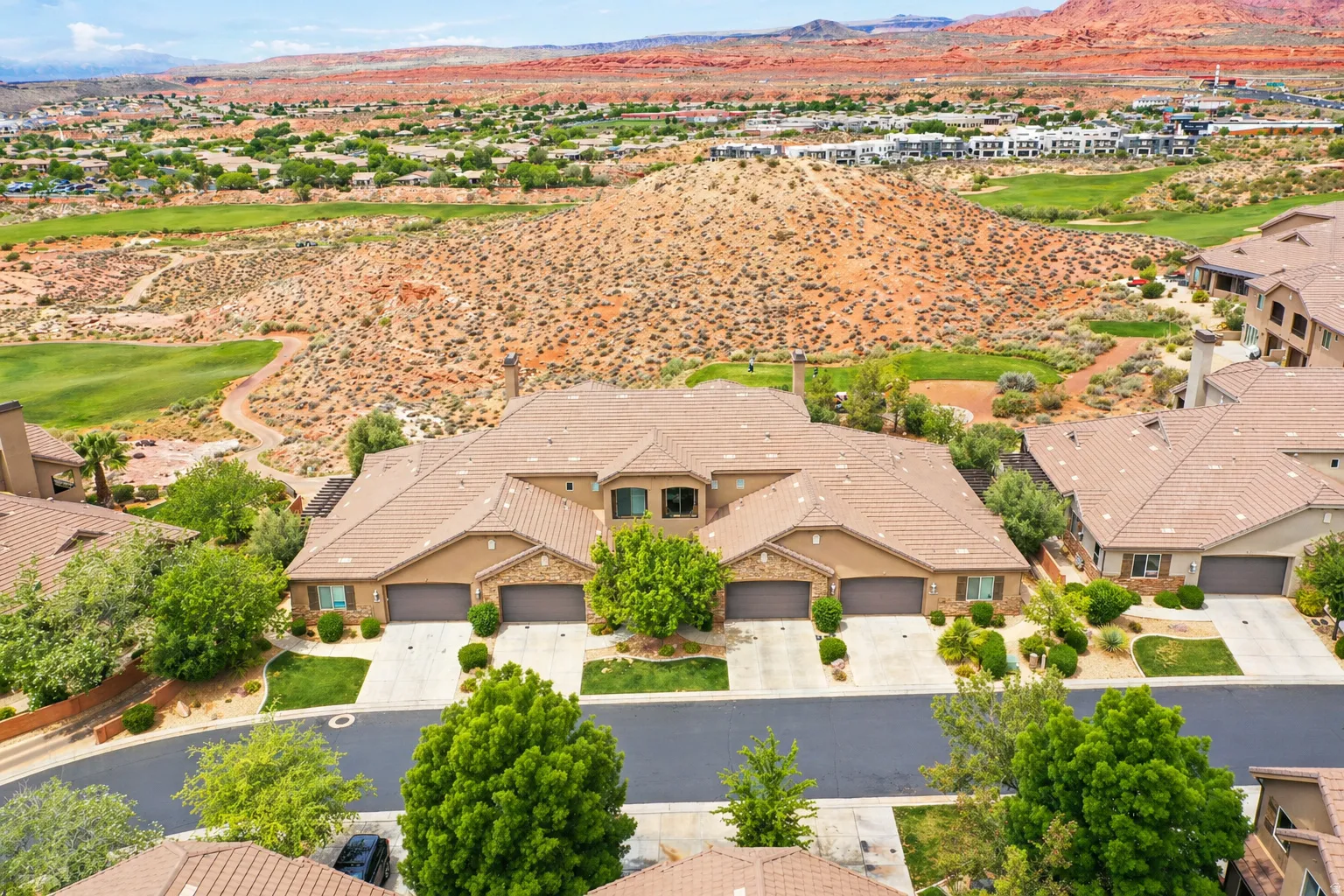 Aerial perspective of suburban area featuring a mountain backdrop and a golf club