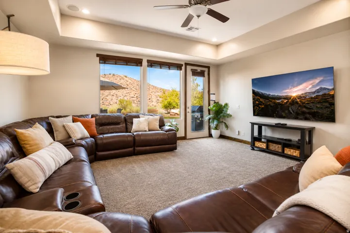 Recessed lighting, ceiling fan, and tray ceiling in a carpeted living space with a glass-paneled door