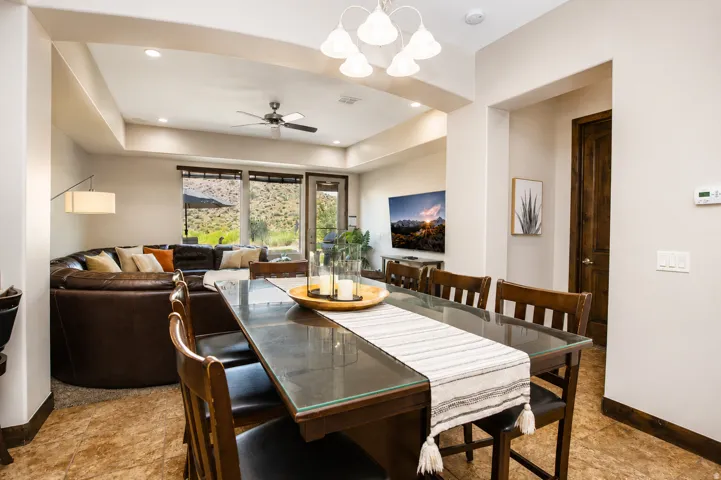 Recessed lighting in living area, ceiling fan, large windows with natural scenery, contemporary chandelier, and wood-finish door